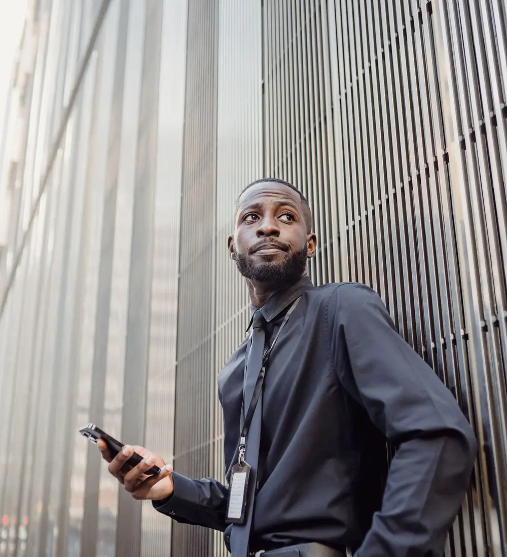 Jeune professionnel consultant son téléphone devant un bâtiment